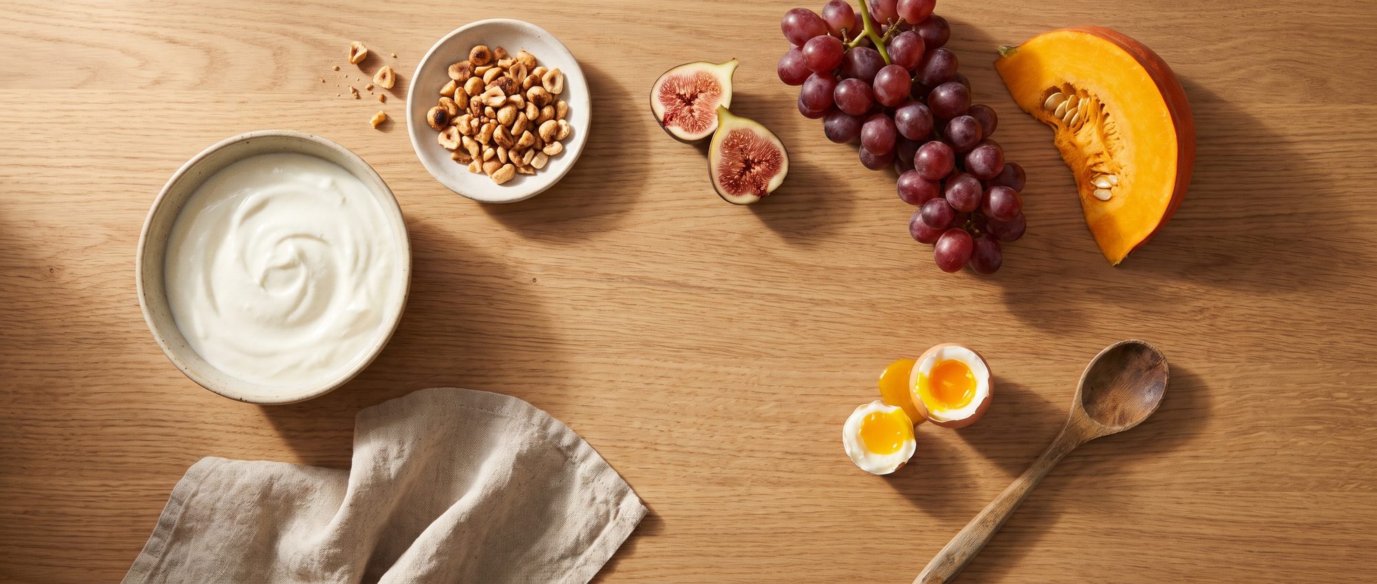 Iogurte, castanhas, figos, uvas, abóbora e ovo sobre a bancada de madeira